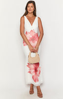 Girl wearing floral print maxi dress and white heels holding a cocktail glass.