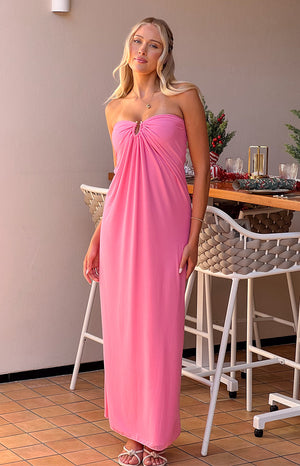 Blonde girl wearing a pink maxi dress and nude heels in front of christmas lunch table.
