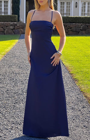 A sleek navy blue satin maxi dress, ideal for a formal or prom event, featuring thin spaghetti straps and a clean, elegant silhouette.