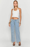 model styled in low rise blue denim jeans with sequin detailing around pocket, white heels and white mini bag