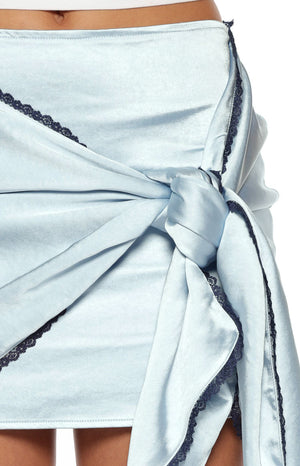 Close up of a girl showing the knotted detail and contrast lace trim on a blue satin mini skirt for a dressy occasion