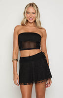 blonde girl wearing a black strapless lace and mesh top with a matching black a-line mini skirt and gold jewellery